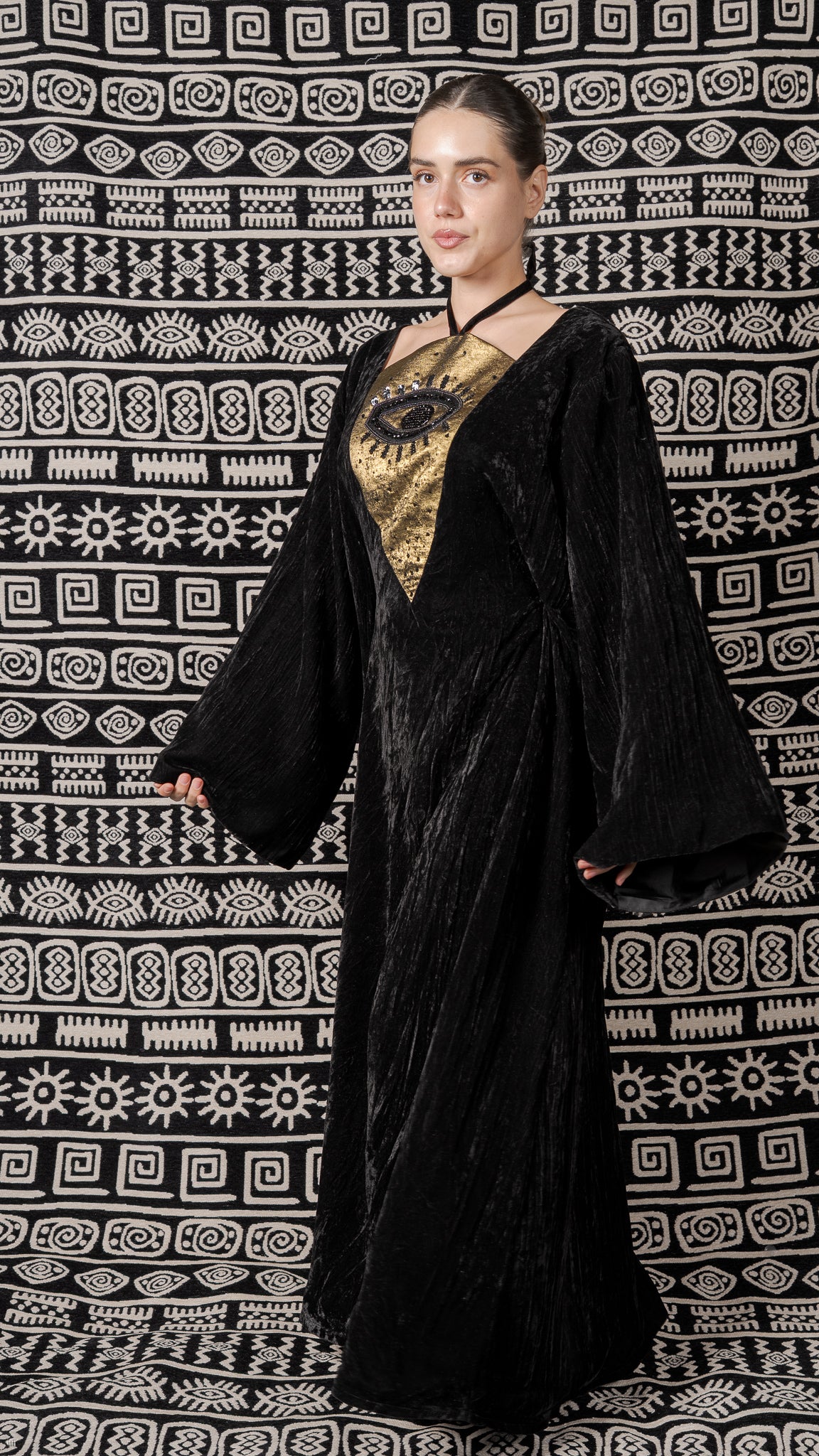 Woman wearing a black and gold outfit against a patterned background
