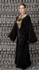Woman wearing a black and gold outfit against a patterned background