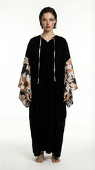 Woman wearing a black dress with floral sleeves on a white background