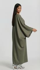 Woman wearing a long olive green dress on a white background