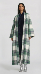 Woman wearing a long plaid coat on a white background