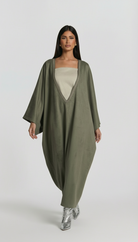 Woman wearing a long olive green dress with a plain white background